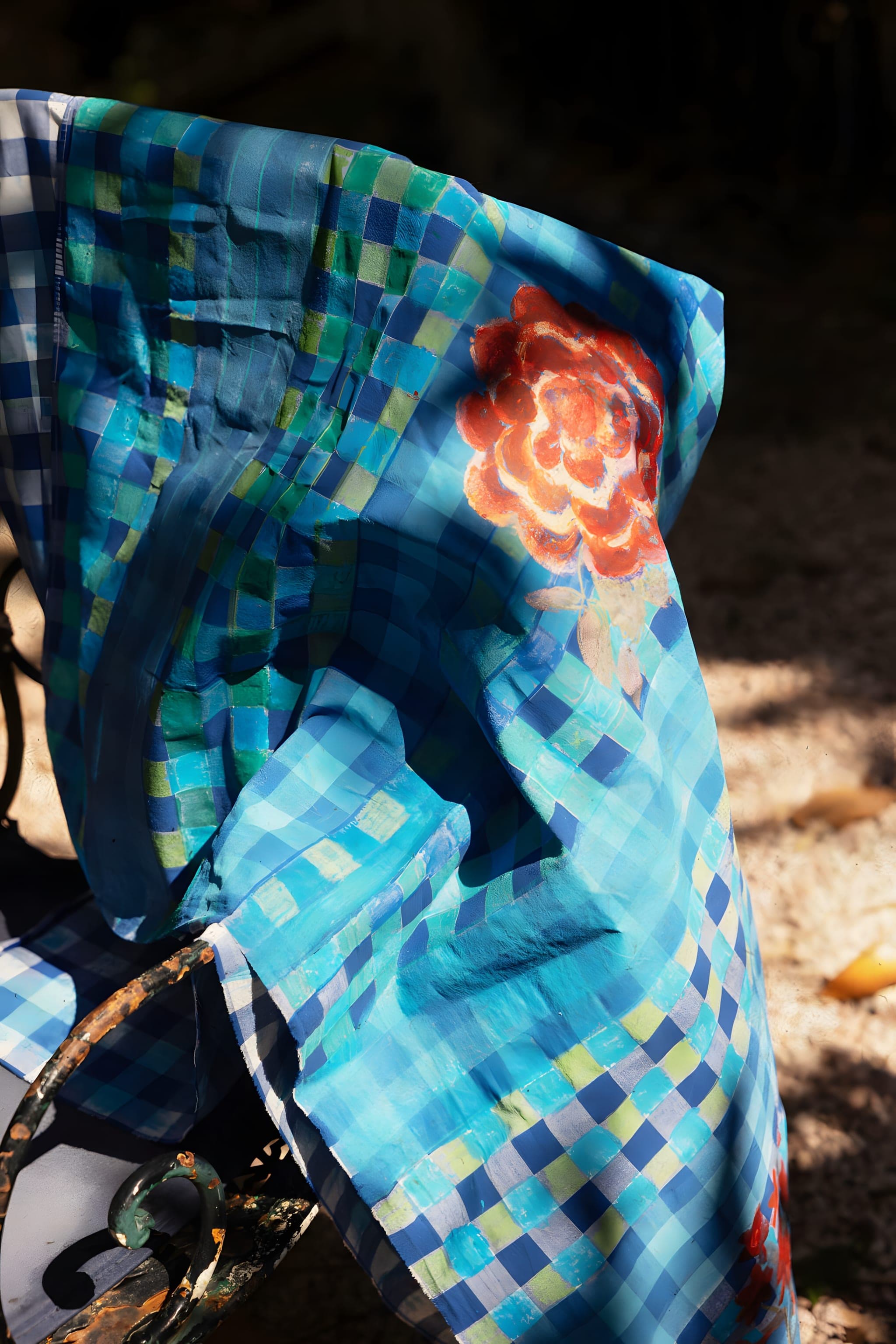Un linge bleu à carreaux brodé d'une rose, dans la lumière du soleil
